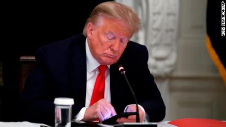Były prezydent Donald Trump patrzy na swój telefon podczas okrągłego stołu z gubernatorami stanów na temat ponownego otwierania małych firm w Ameryce, w jadalni Białego Domu w Waszyngtonie, 18 czerwca 2020 r. 