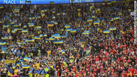 Kibice z Ukrainy wznoszą flagę swojego kraju na stadionie Cardiff City. 