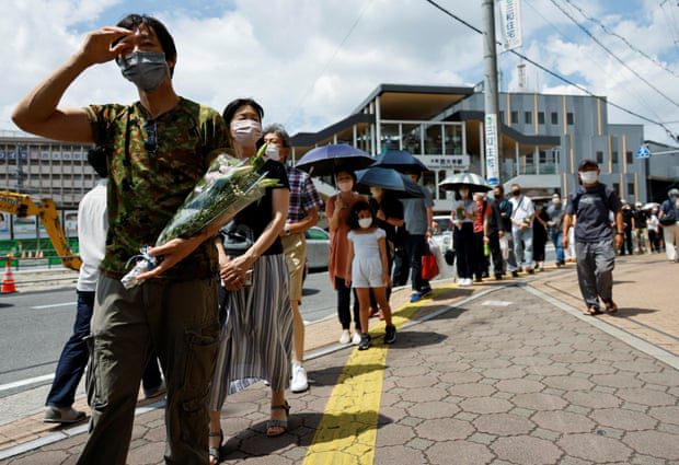 Ludzie ustawiają się w kolejce, aby dać kwiaty i modlić się w miejscu, gdzie Shinzo Abe został ranny