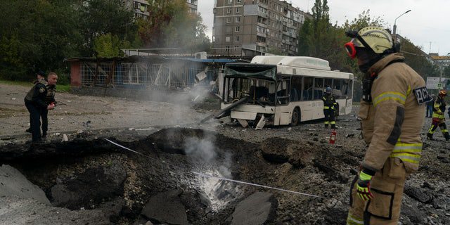 Strażacy i policjanci pracują w miejscu, gdzie eksplozja stworzyła krater na ulicy po rosyjskim ataku w Dnieprze na Ukrainie, poniedziałek, 10 października 2022 r. (AP Photo/Leo Correa)