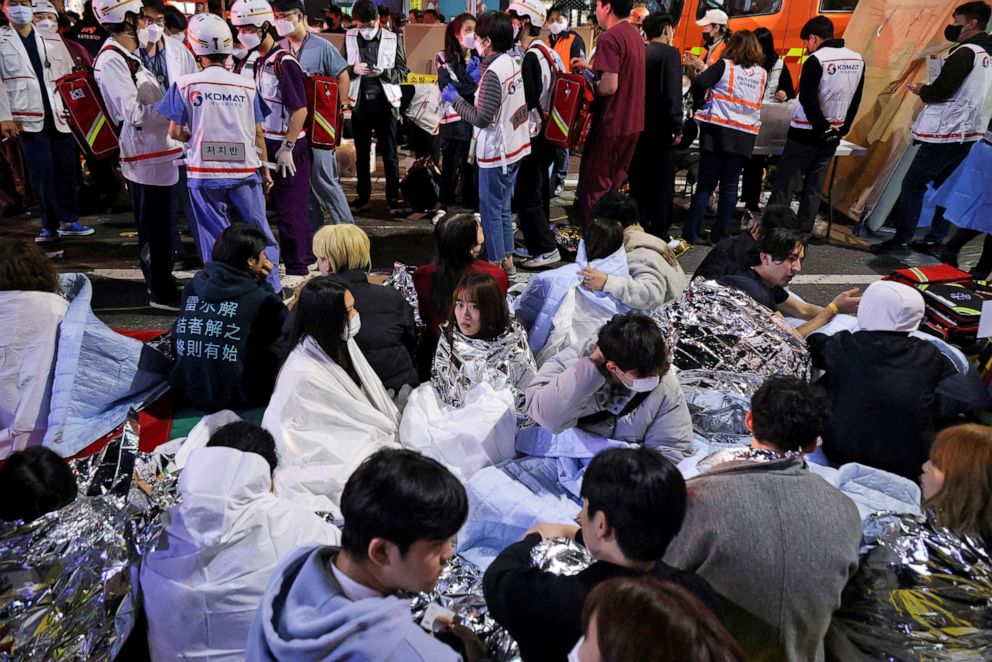 Zdjęcie: Ludzie siedzą na ulicy po uratowaniu, na miejscu kilkudziesięciu osób rannych w panice podczas obchodów Halloween w Seulu w Korei Południowej, 30 października 2022 r.