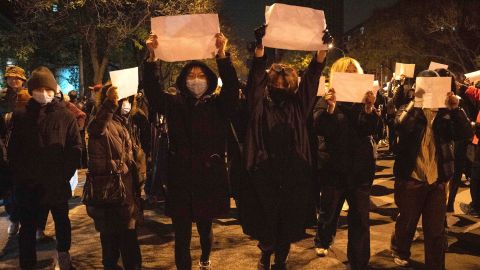 Demonstranci trzymają puste kartki i wykrzykują hasła podczas wiecu protestacyjnego w Pekinie w niedzielę wieczorem. 